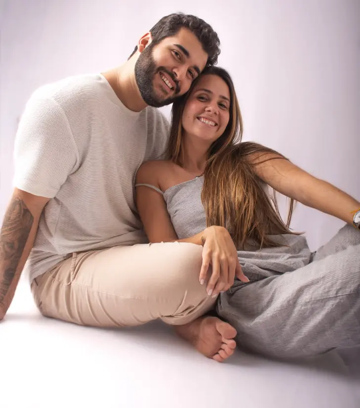 Casal sentado no chão do estúdio, abraçado e sorrindo