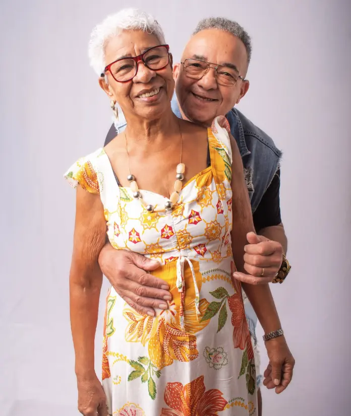 Casal de idosos sorrindo, abraçado, em ensaio no estúdio